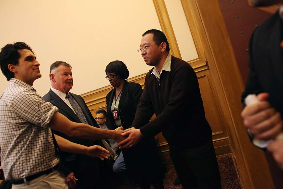 Alan Yam (right), who was driving the Muni bus that was set on fire after the Giants' World Series win, and Simon Timony (left), who tried to prevent the crowd from vandalizing the Muni bus after the Giants' World Series win, shake hands before a ceremony honoring them at City Hall on Tuesday, November 6, 2012 in San Francisco, Calif.