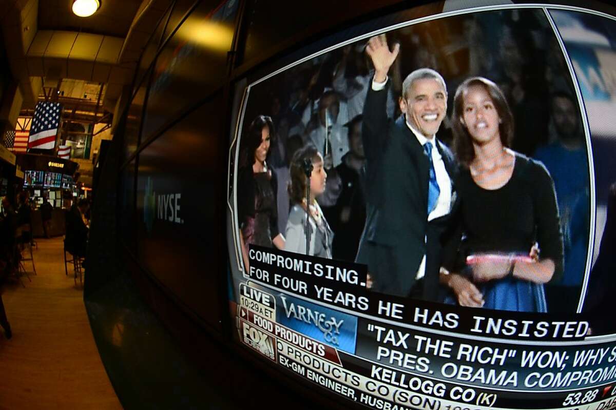 A television feed on the floor of the New York Stock Exchange shows Pres. Barack Obama, left, and his daughter, Malia, the day after he was re-elected, Wednesday, Nov. 7, 2012 in New York. With President Barack Obama elected to another term, U.S. investors dumped stocks Wednesday and turned their focus to a world of problems, including a "fiscal cliff" of tax increases and spending cuts at home and a deepening recession in Europe. (AP Photo/Henny Ray Abrams)