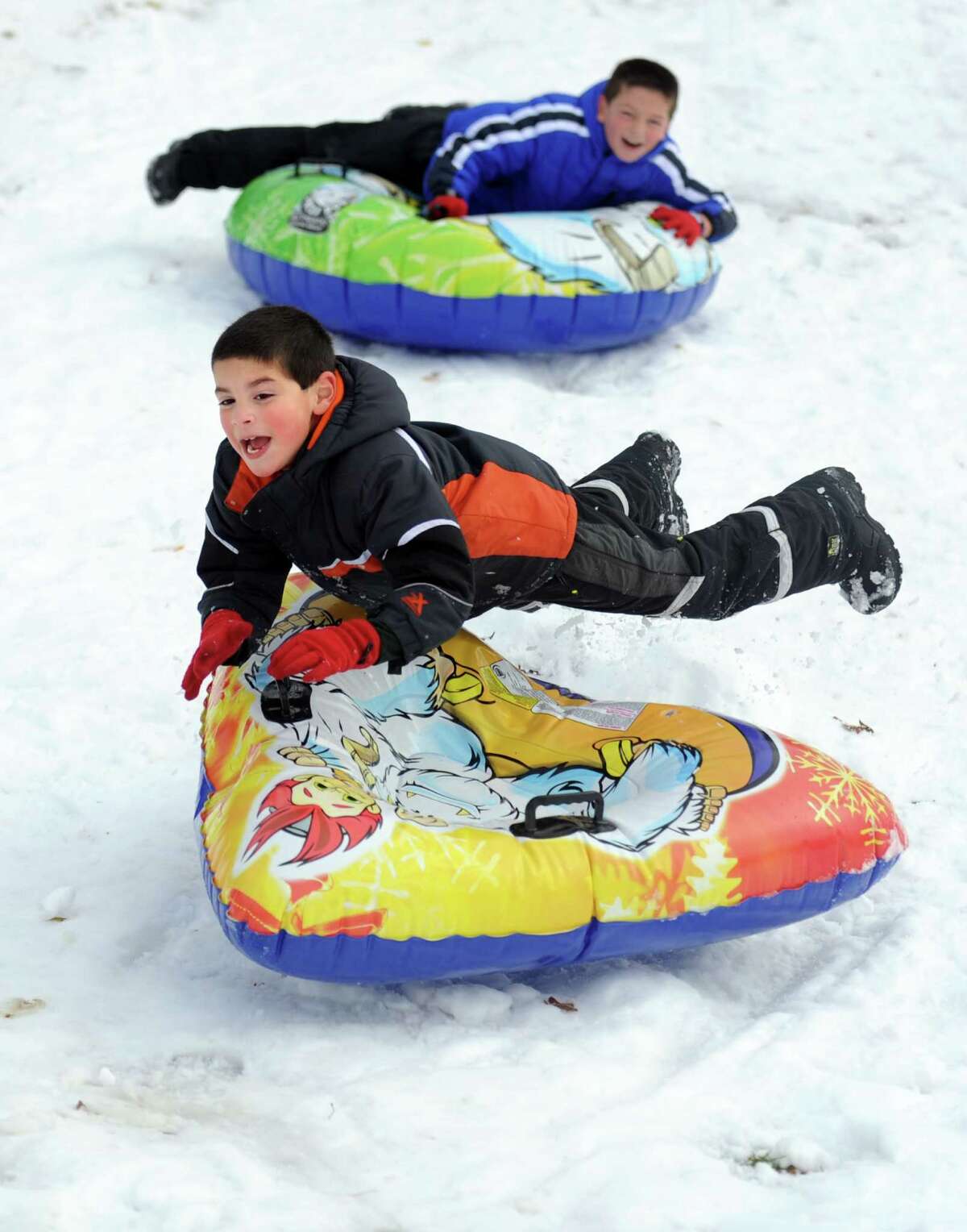 Michael Anroman, 7, of Seymour, goes over a bump while sledding behind Derby Middle School Thursday, Nov. 8, 2012 followed by his brother Johnny, 9.