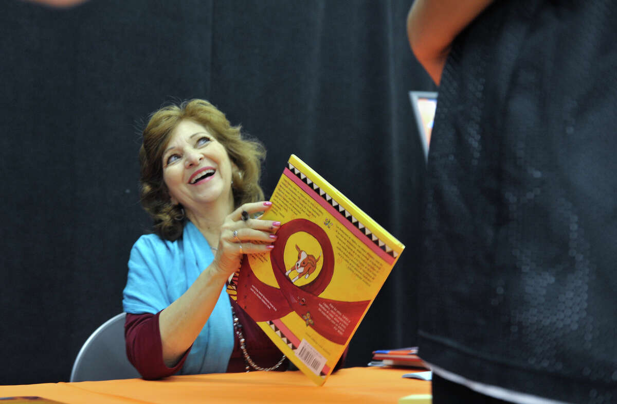 San Antonio author and poet laureate Carmen Tafolla laughs while signing a copy of her book, "Rebozos," during the 9th annual San Antonio Express-News Children's Book Celebration Saturday at the Tripoint YMCA.