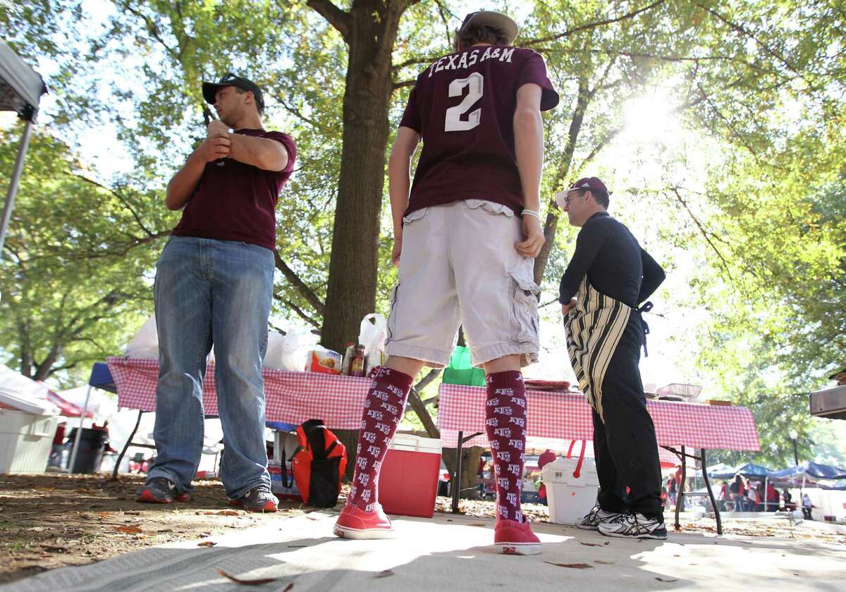 Sporting a Johnny Manziel No. 2 jersey, Brandon Neely, 17, of Waco, tailgates with Mitchell Long, a junior at Texas A&M, left, and Joe Calao of Waco before Saturday's game at Tuscaloosa, Ala., in which the Aggies upset Alabama 29-24.