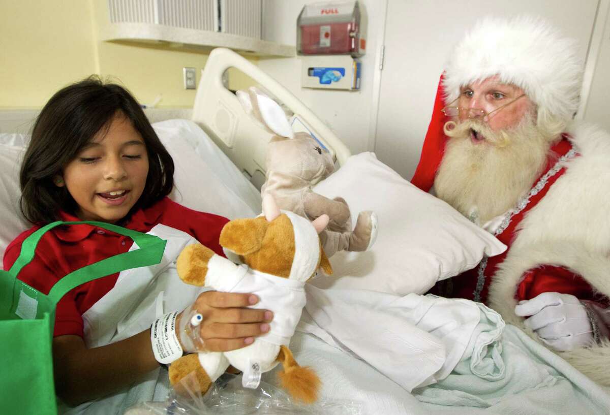 Santa Claus brings a gift to Karla Burden, 11, during a mini holiday parade through the hallways of Texas Children's Hospital on Tuesday, Nov. 13, 2012, in Houston.