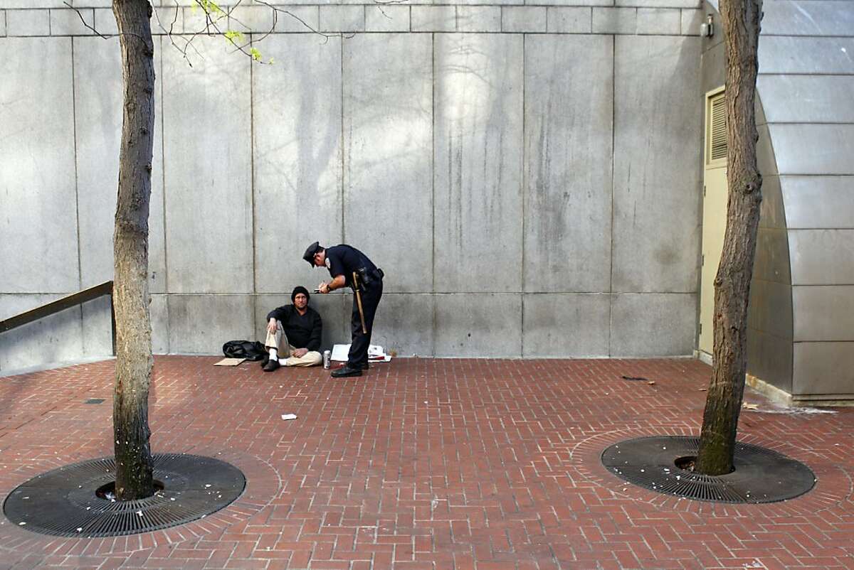 At the Powell Street BART station entrance, San Francisco police officer James Tacchini writes a citation to a man drinking in public as he and his partner, Officer Barry Mlaker walk their beat near Market Street in San Francisco, Calif., looking for chronic law breakers on Wednesday, November 14, 2012.