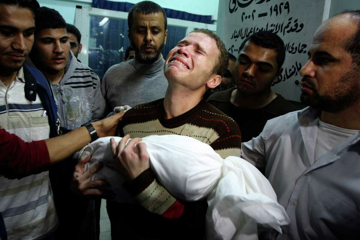 Jihad Masharawi weeps while he holds the body of his 11-month old son Ahmad, at Shifa hospital following an Israeli air strike on their family house, in Gaza City, Wednesday, Nov. 14, 2012. The Israeli military said its assassination of the Hamas military commander Ahmed Jabari, marks the beginning of an operation against Gaza militants. (AP Photo/Majed Hamdan)