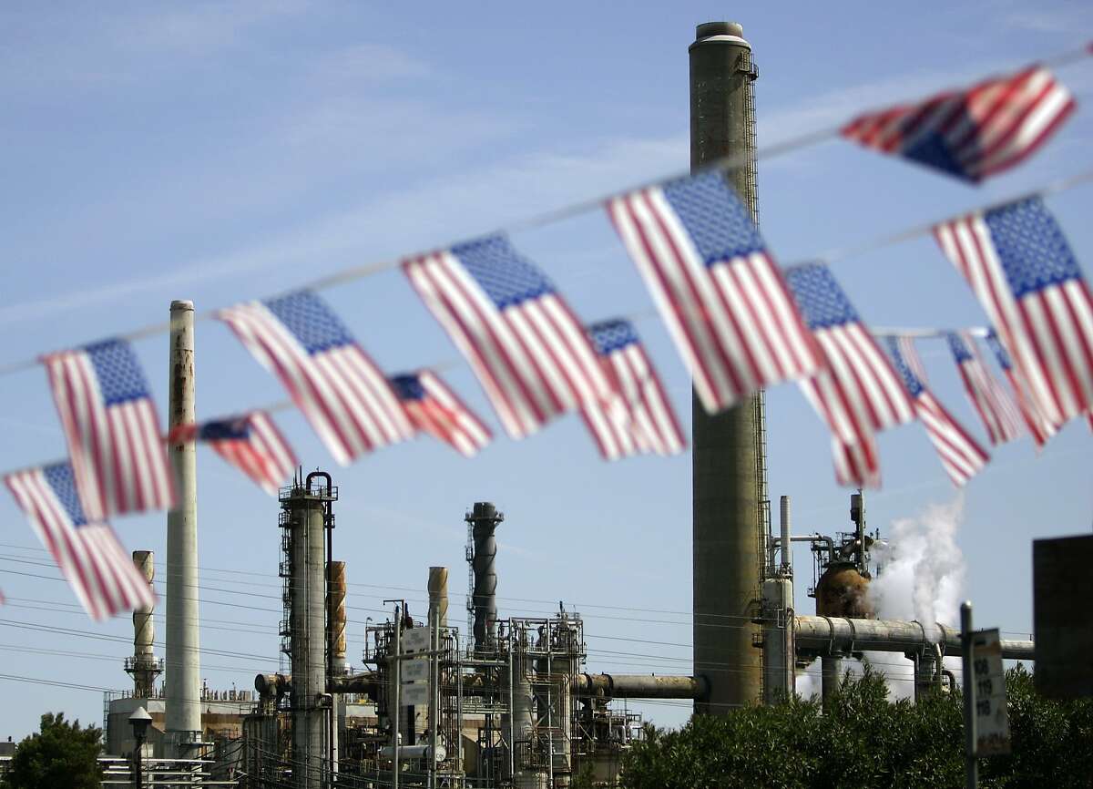 In this April 30, 2008 file photo, American flags are seen near the Shell refinery, in Martinez, Calif. On Weds., Nov. 14, 2012, California's largest greenhouse gas emitters will for the first time begin buying permits in a landmark "cap-and-trade" system meant to control emissions of heat-trapping gases and spur investment in clean technologies. The program is a key part of California's 2006 climate-change law, AB32, a suite of regulations that dictate standards for cleaner-burning fuels, more efficient automobiles and increased use of renewable energy. (AP Photo/Ben Margot, File)