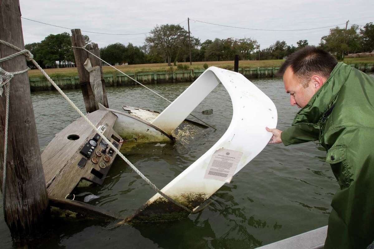 Craig Cook, of the Texas General Land Office, inspects an abandoned boat near Dickinson Bayou in Texas City. The state removal program, funded primarily by federal grants, has 297 derelict boats on its waiting list.