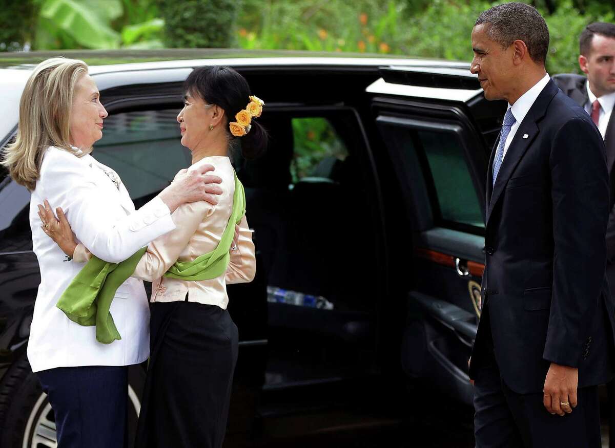 President Barack Obama watches as Myanmar democracy activist Aung San Suu Kyi greets Secretary of State Hilary Rodham Clinton at her residence in Yangon, Myanmar, on Monday.