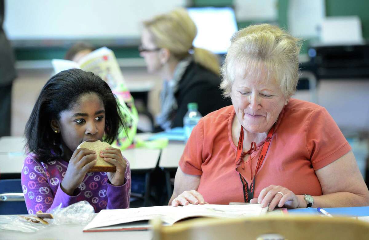 Ann Terry, right reads to Aonya Lewis during the "Everybody Wins!" Power Lunch, a Literacy Volunteers of Rensselaer County program, in which elementary school children are paired with volunteer mentors who read to them during their lunch period at Sacred Heart School in Troy, N.Y. Nov 13, 2012. (Skip Dickstein/Times Union)