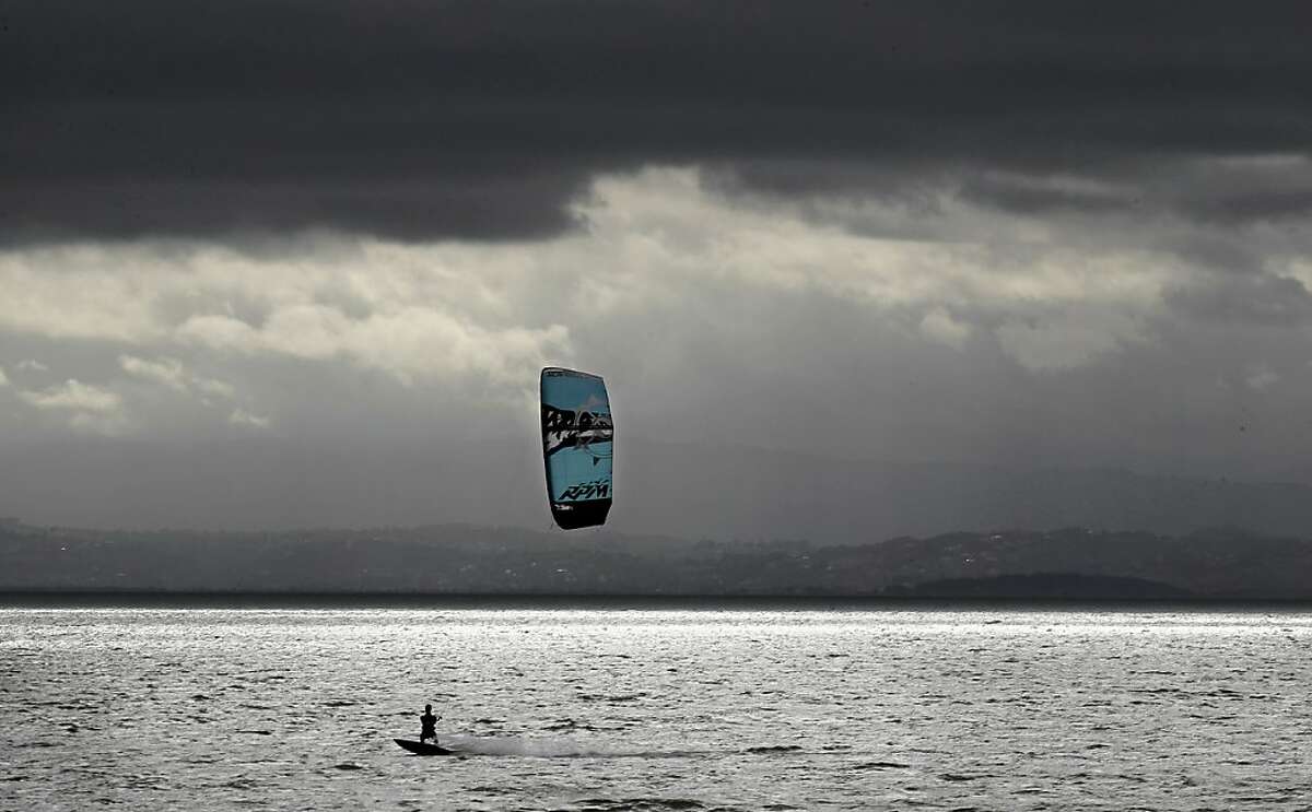 A kiteboarder slips into the Bay at Crown Memorial State Beach in Alameda, Ca. on Tuesday Nov. 20, 2012,under partly cloudy skies as a rain storm is expected later this afternoon.