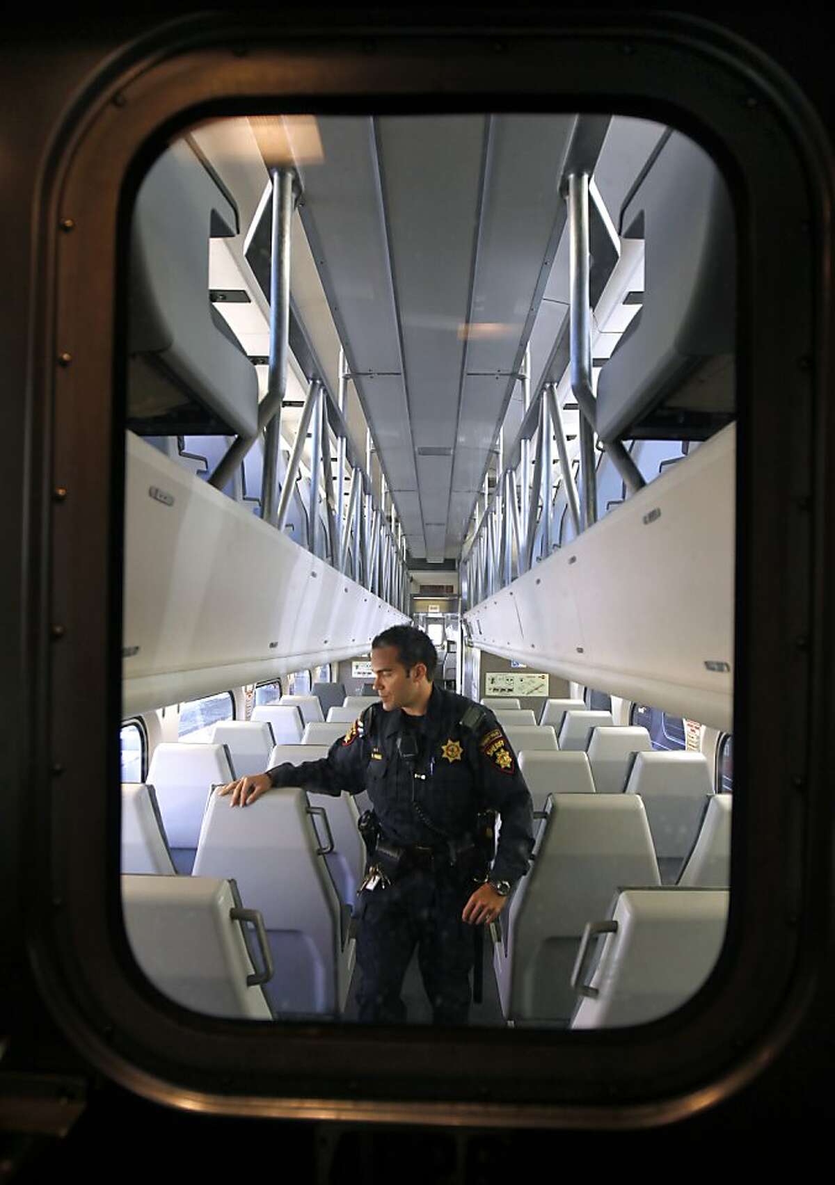 San Mateo County Sheriff's Deputy Brandon Hensel, assigned to the transit patrol detail, walks through an empty train at the Caltrain station in San Francisco, Calif. before it heads southbound on Wednesday, Aug. 8, 2012.