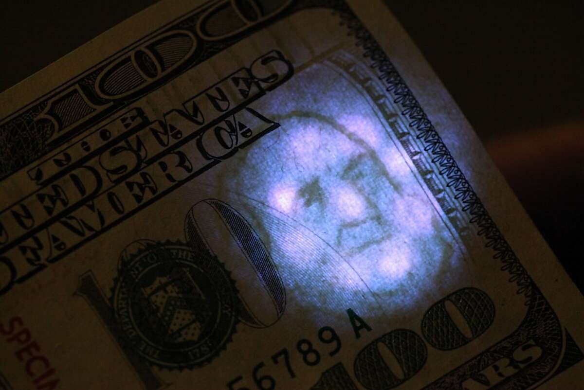 A watermark on a real $100 bill is seen under a black light at the United States Secret Service San Francisco Field Office on Thursday, November 15, 2012 in San Francisco, Calif.