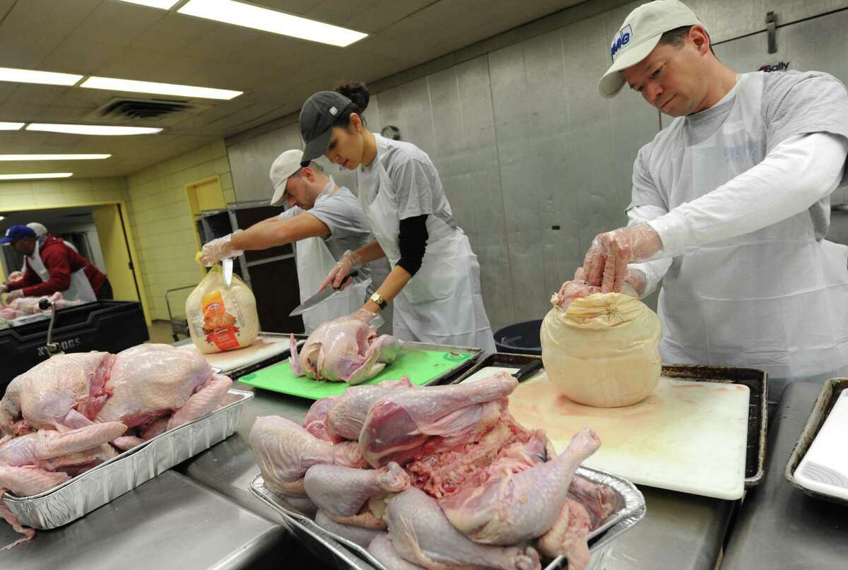 Volunteer from KPMG, left to right, Dominick Caldarazzo, Zamira Akchurina and Dean Geesler prep turkey for the Equinox Thanksgiving Dinner at the Empire State Plaza in Albany, NY Tuesday Nov. 20, 2012. (Michael P. Farrell/Times Union)