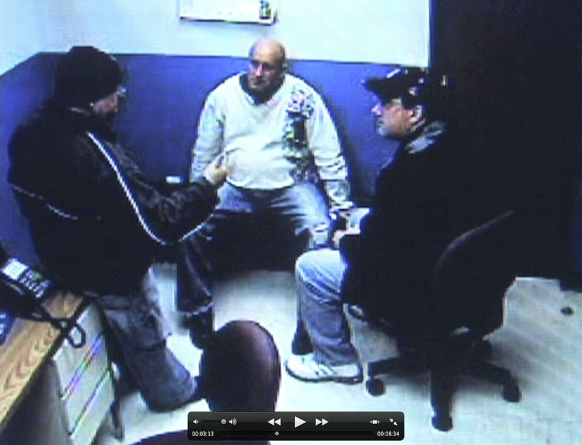 Frame grab from stationhouse video footage of Albany police officer Brian Lutz?s, center, arrest in Menands. Albany police officer, Charles Batchelor, left, and former Albany police union president, Christian Mesley, right, are shown counseling officer Lutz. (Times Union)