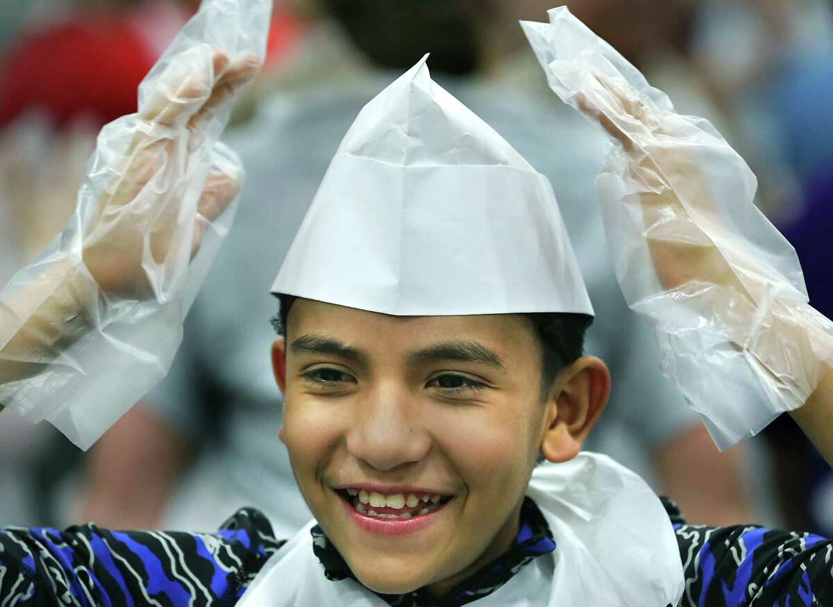 Matthew Garcia, right, talks to his sons Wyatt Garcia, 6, left, and Ryan Garcia, 5, center, about helping hands as they volunteer to serve at the Raul Jimenez Thanksgiving Dinner at the Henry B. Gonzalez Convention Center, Thursday, Nov. 22, 2012.