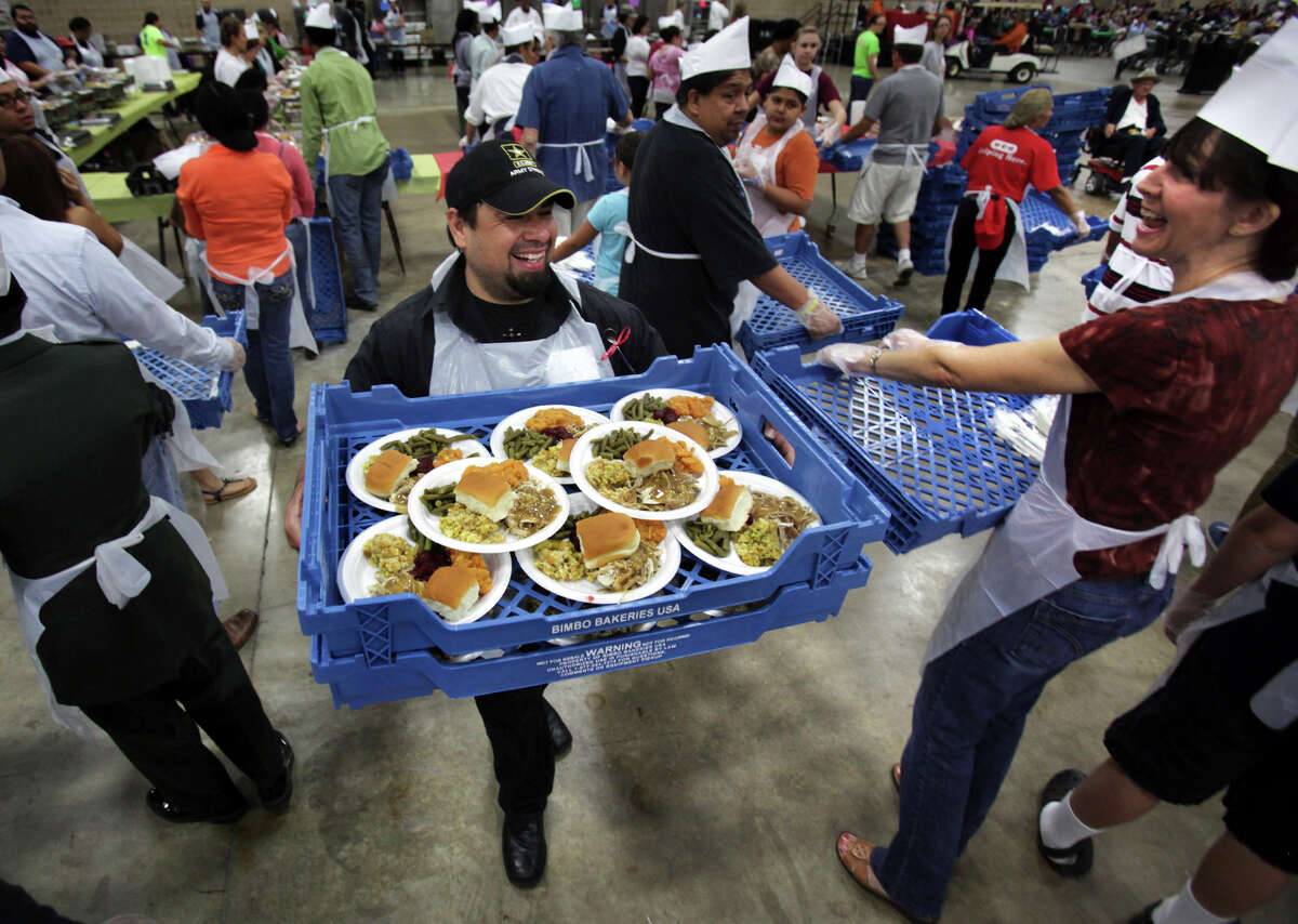 Elvis Hernandez, center, smiles as he carries two trays full of turkey dinners to serve them to seniors and people in need, at the Raul Jimenez Thanksgiving Dinner at the Henry B. Gonzalez Convention Center, Thursday, Nov. 22, 2012.