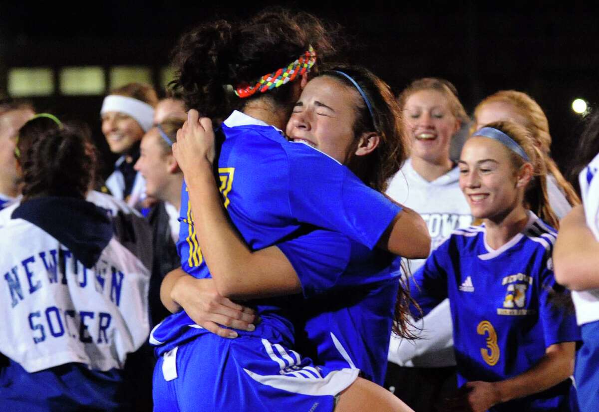 Newtown's #11 Brittany Tolla and #6 Bridget Power, facing camera, share a hug after the team defeated Glastonbury, during Class LL girls soccer championship action in West Haven, Conn. on Friday November 23, 2012.