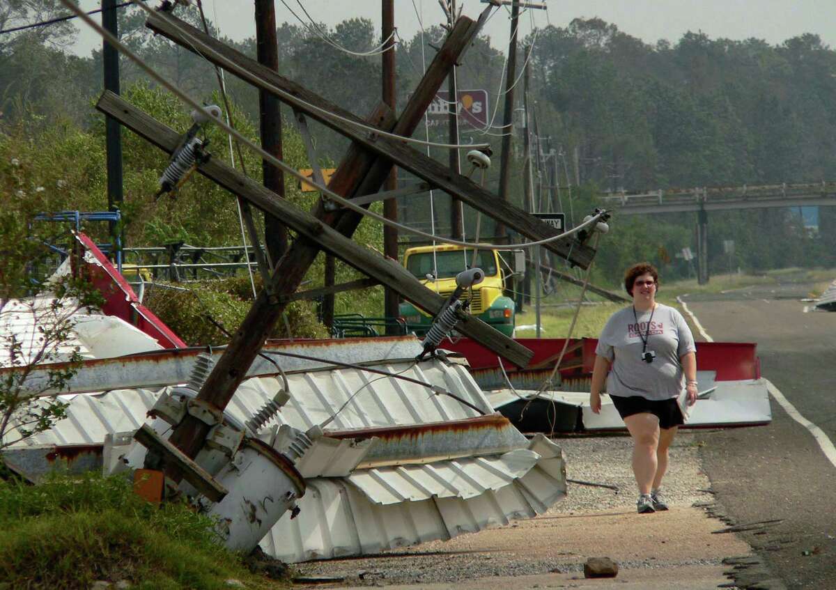 Reporter Amy Dorsett of the San Antonio Express-News walks along a road devastated by Hurricane Rita in Beaumont, Texas, on Sept. 25, 2005. Dorsett and photographer Billy Calzada had been in Lousiana covering the effects of Hurricane Katrina, when, on their way back to San Antonio, the Beaumont area was hit by Hurricane Rita. Dorsett died in San Antonio on November 22, 2012 after an extended illness.