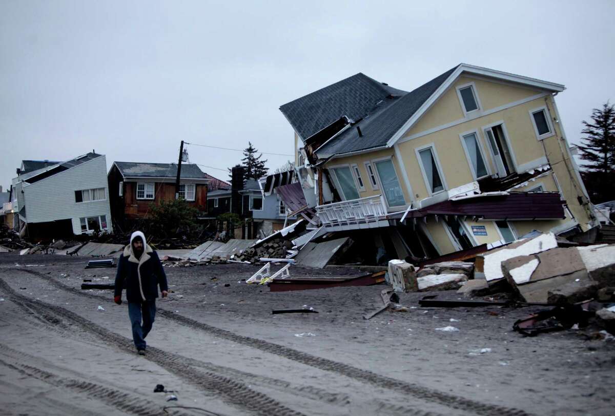 A man walks past destroyed homes on the Rockaway Peninsula in Queens, New York, Tuesday, Nov. 27, 2012. Officials say New York City's free repair program for storm-damaged homes has fixed up about 50 homes so far, while still just gearing up. (AP Photo/Seth Wenig)