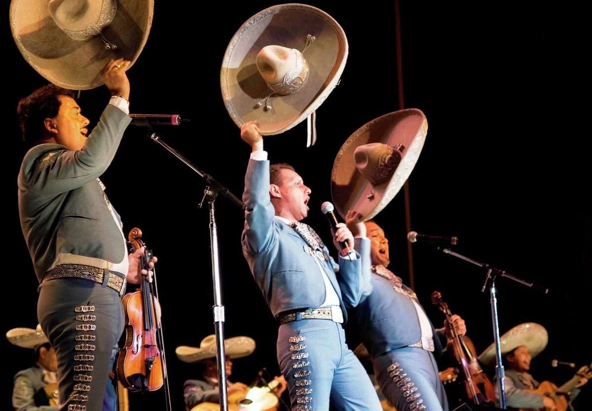 Members of Mariachi Vargas de Tecalitlan wave their sombreros during a performance