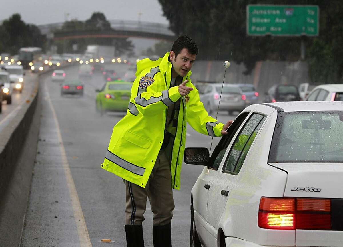 California Highway Patrol officer Mike Ferguson gives instructions to a driver involved in a minor three car accident on southbound Highway 101 near Cesar Chavez Boulevard during Friday's rainstorm in San Francisco, Calif. on Nov. 30, 2012.