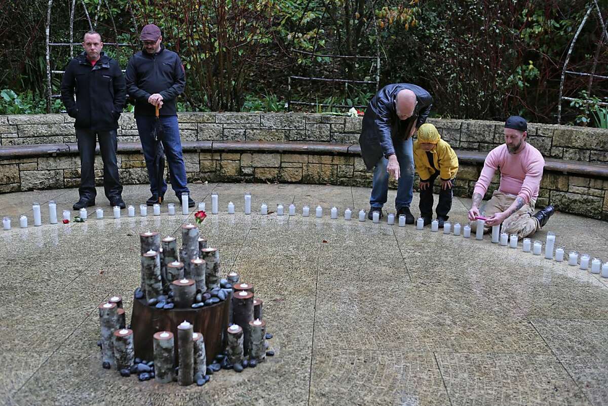 Steven Dibner (third from right) and son Pablo Dibner search for the etched name of the late Wayne Parrish, a friend and colleague in the San Francisco Symphony, at the "Circle of Friends" in the AIDS Memorial Grove. Friends and family came to find names of supporters and those who have passed away at the "Circle of Friends" at the AIDS Memorial Grove in Golden Gate Park, San Francisco, Calif. Saturday marked the 19th annual world AIDS day remembrance, with a national AIDS memorial service at the Grove designed to remember the dead and raise awareness for the living.