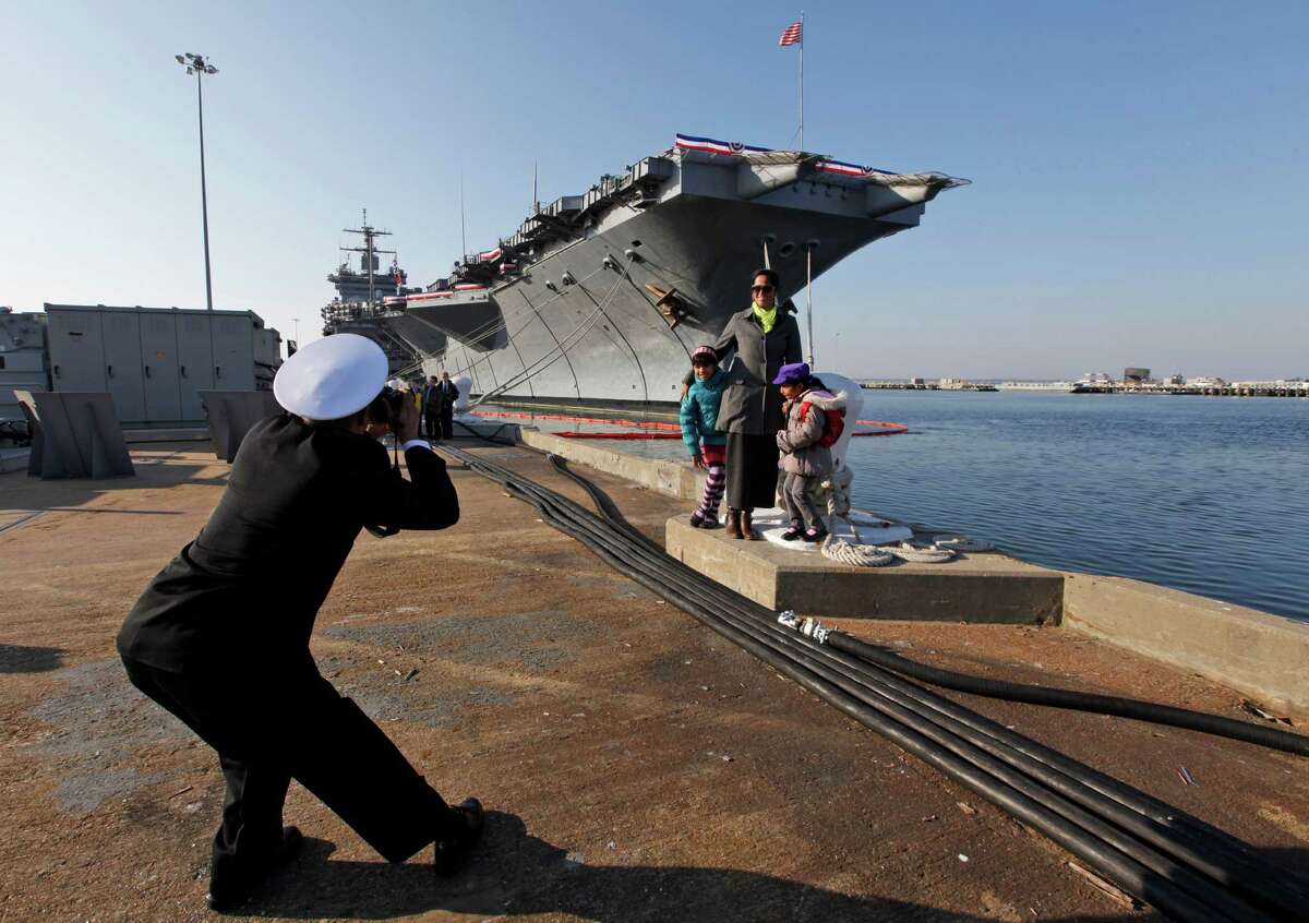 Senior Chief Nageer Rahim, originally from Guyane, photographs his wife, Aliya and their kids in front of the USS Enterprise after an inactivation ceremony for the first nuclear powered aircraft carrier USS Enterprise at Naval Station Norfolk Saturday, Dec. 1, 2012 in Norfolk, VA. The ship served in the fleet for 51 years. (AP Photo/Steve Helber)