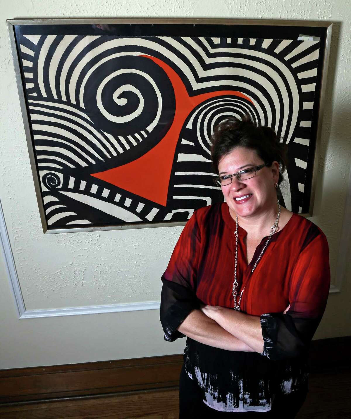 In this Wednesday, Nov. 28, 2012 photo, Karen Mallet stands in front of her Alexander Calder print in her Shorewood, Wis., home. Mallet bought the print for $12.34 at a Goodwill thrift store in Milwaukee. It turned out to be a lithograph by the American artist Alexander Calder worth $9,000. (AP Photo/Morry Gash)