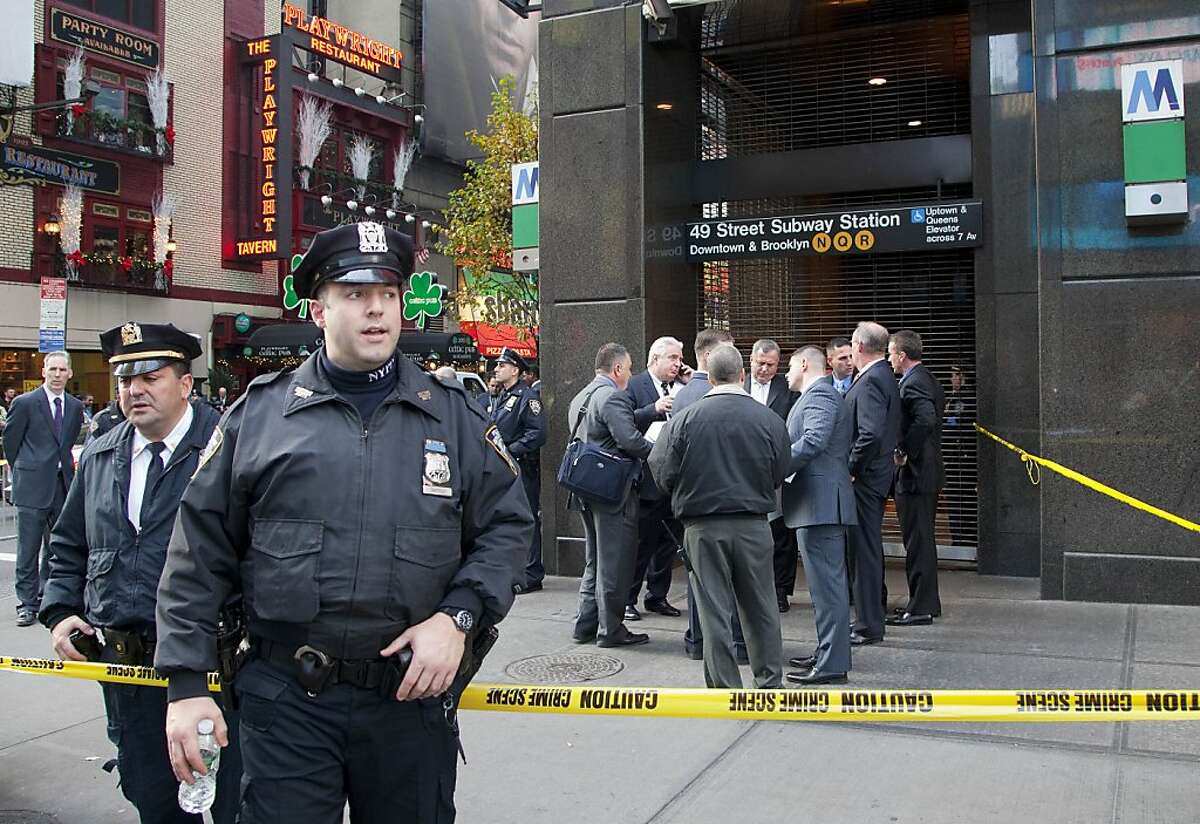 Uniformed and plainclothes police officers stand outside a New York subway station after a man was killed after falling into the path of a train, Monday, Dec. 3, 2012. Transit officials say police are investigating whether he could have been pushed onto the tracks. (AP Photo/Mark Lennihan)