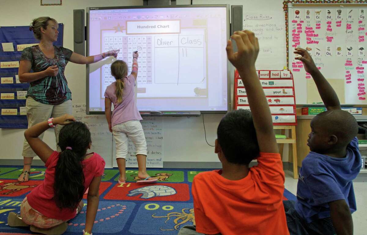First grade teacher, Susanne Oliver, instructs Jesica Evans, 7, at a SMART Board, an interactive whiteboard, during summer school at Lovett Elementary, 8814 South Rice Ave.