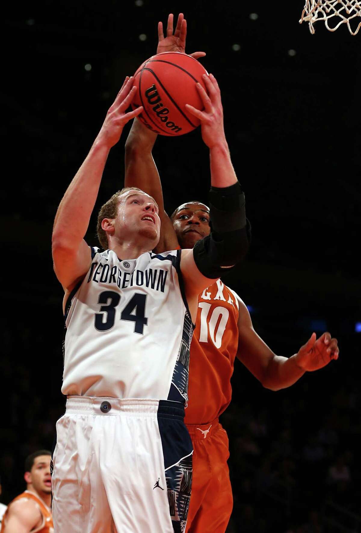Nate Lubick #34 of the Georgetown Hoyas takes a shot as Jonathan Holmes #10 of the Texas Longhorns defends during the Jimmy V Classic on December 4, 2012 at Madison Square Garden in New York City.