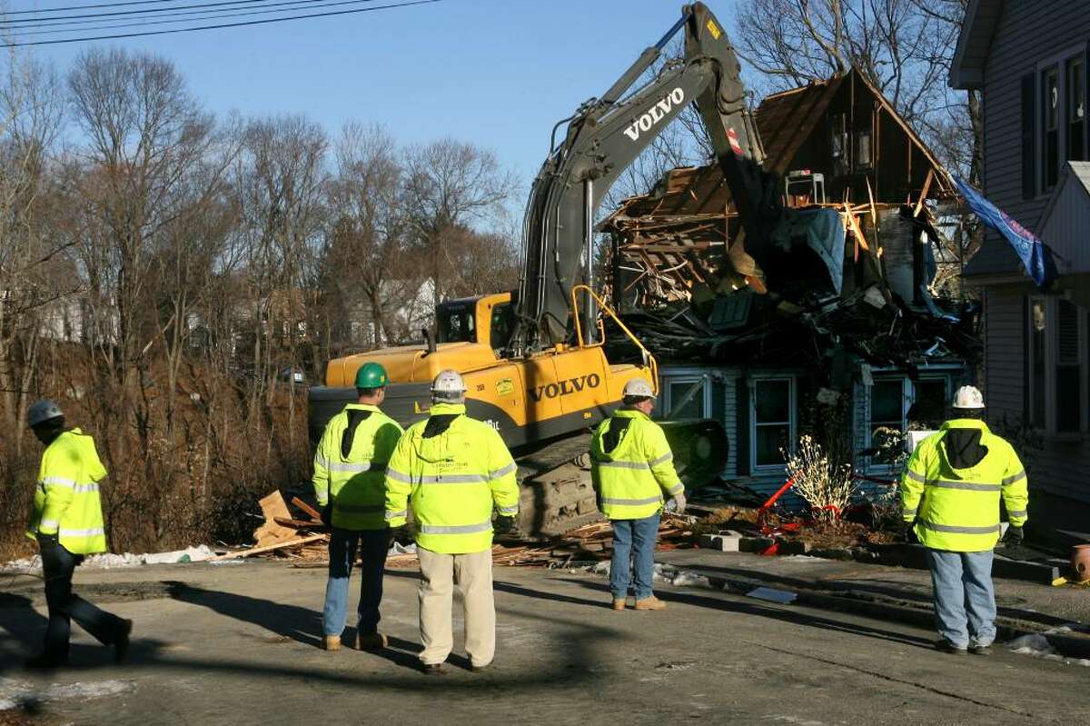 A home on 161 North Oak Drive in Shelton is demolished on Friday, Dec. 18, 2009. The vacant home was in danger of collapsing after a mudslide and posed a threat to the Riverview Condominium complex below it.