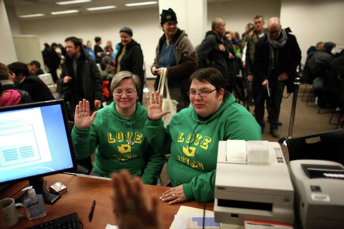 Jennifer Traband, left, and Emme Scheible give an oath that their information is accurate as same-sex couples are issued marriage licenses at the King County Administration Building shortly after midnight on Thursday, December 6, 2012.