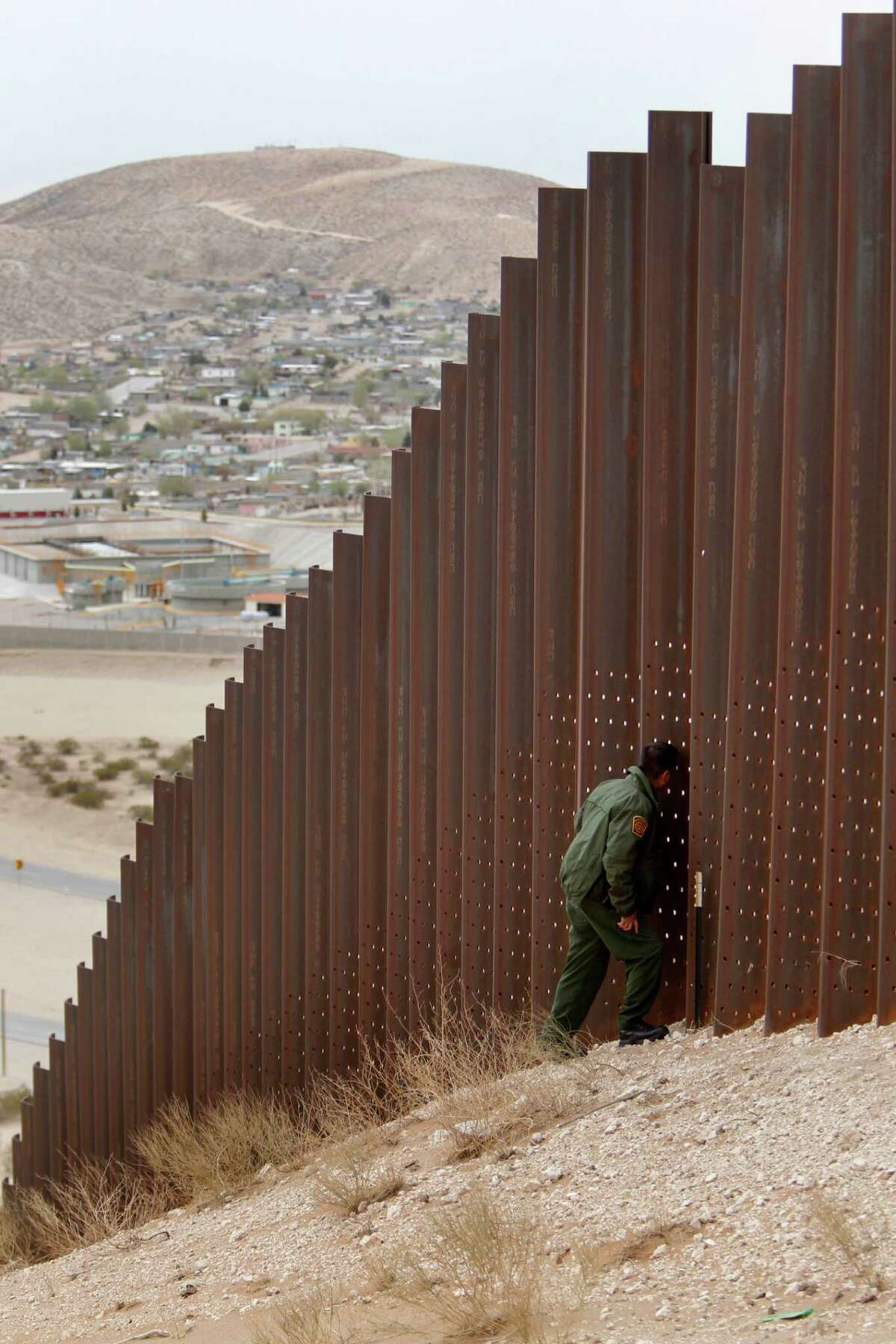 Border Patrol Agent Jacob Nunez peers through the border fence near Sunland Park, New Mexico. The El Paso Border Patrol sector guards part of the New Mexico-Mexico border.