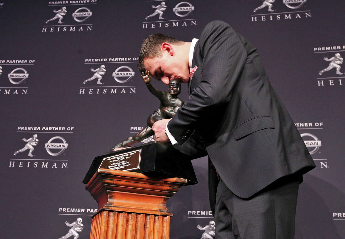 Texas A&M's quarterback Johnny Manziel, the 2012 Heisman Trophy winner, kisses the trophy as he poses for photos during a press conference Saturday Dec. 8, 2012 at the New York Marriott Marquis hotel in New York, New York.