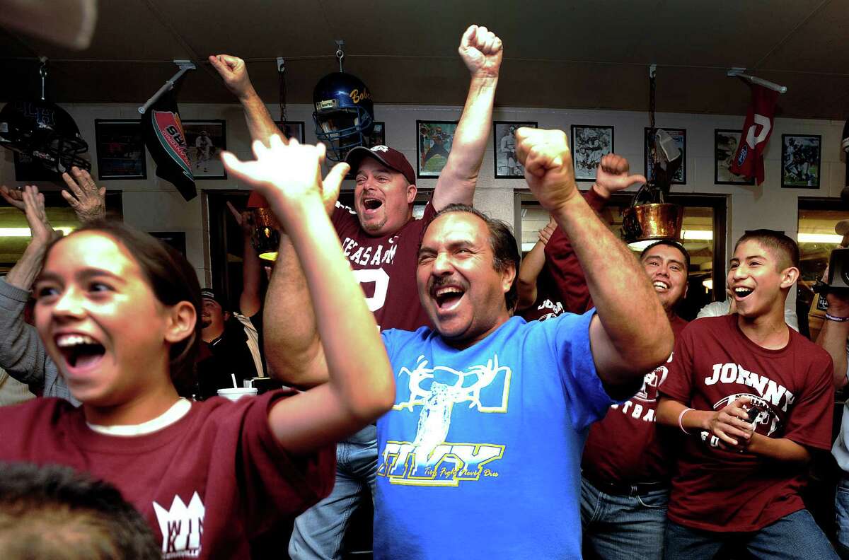 Armando Carranza, middle, and other fans of Texas A&M quarterback Johnny Manziel cheer as Manziel receives the Heisman trophy on television at the Wing King restaurant in Kerrville, Texas, on Saturday night, Dec. 8, 2012. Manziel played high school football for Tivy High School in Kerrville.
