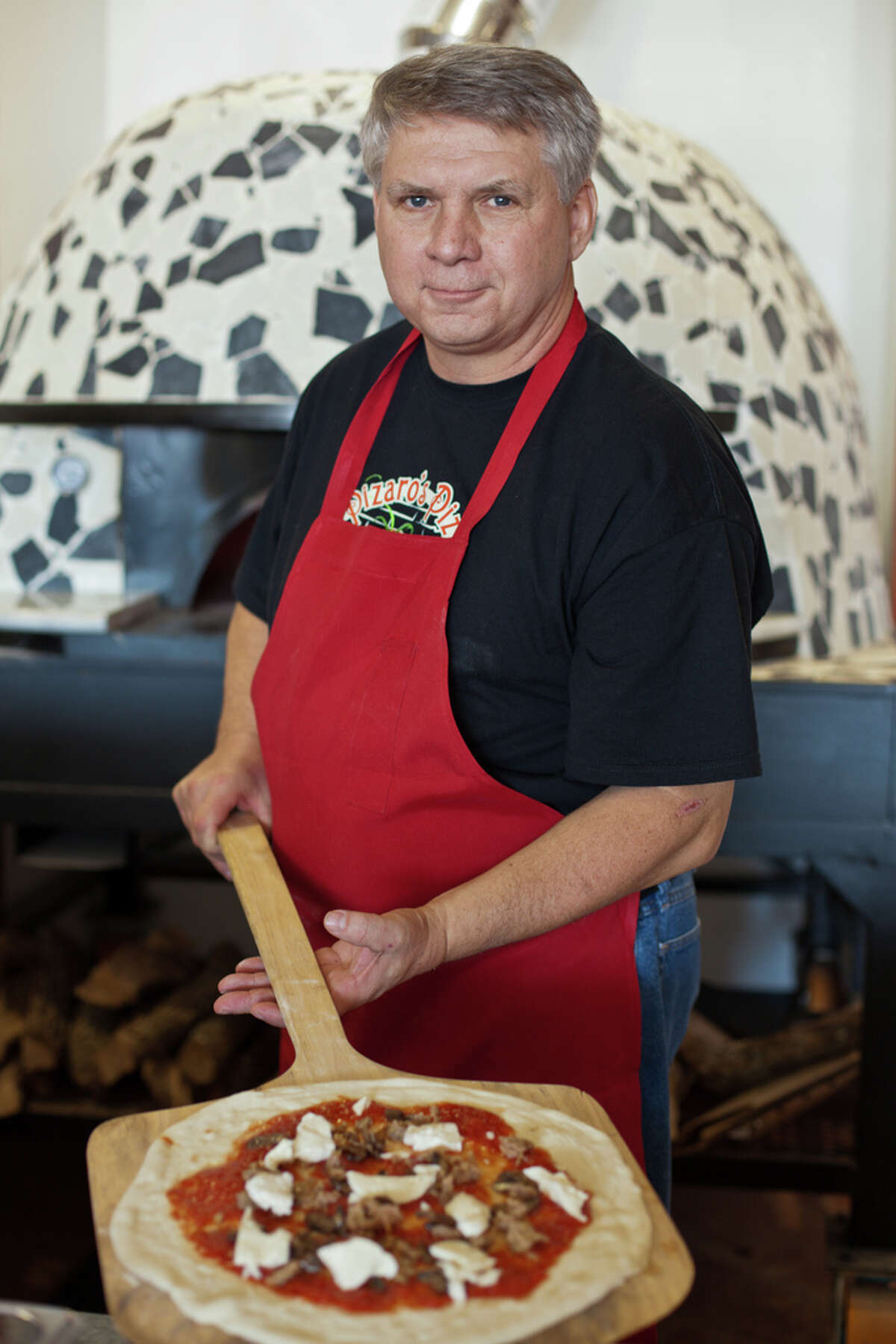 Pizaro's Pizza owner Bill Hutchinson with a pizza ready to go into the wood-fired oven.