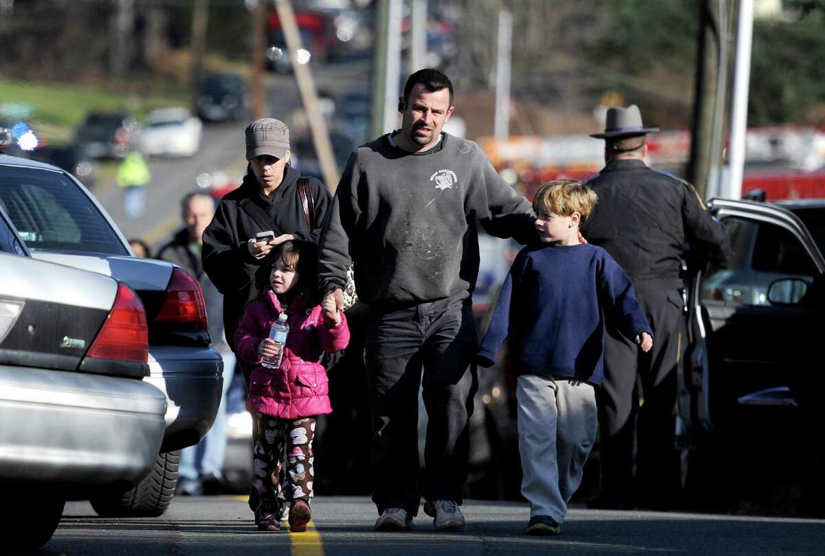 Parents leave a staging area after being reunited with their children following a shooting at the Sandy Hook Elementary School in Newtown, Conn., about 60 miles (96 kilometers) northeast of New York City, Friday, Dec. 14, 2012. An official with knowledge of Friday's shooting said 27 people were dead, including 18 children. It was the worst school shooting in the country's history.