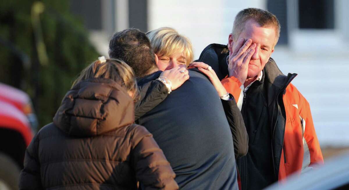 Unidentified people react on December 14, 2012 at the aftermath of a school shooting at a Connecticut elementary school that brought police swarming into the leafy neighborhood, while other area schools were put under lock-down, police and local media said. Local media quoted that the gunman had died at the Sandy Hook Elementary School in Newtown, Connecticut, northeast of New York City. At least 27 people, including 18 children, were killed on Friday when at least one shooter opened fire at an elementary school in Newtown, Connecticut, CBS News reported, citing unnamed officials. AFP PHOTO/DON EMMERT (Photo credit should read DON EMMERT/AFP/Getty Images)