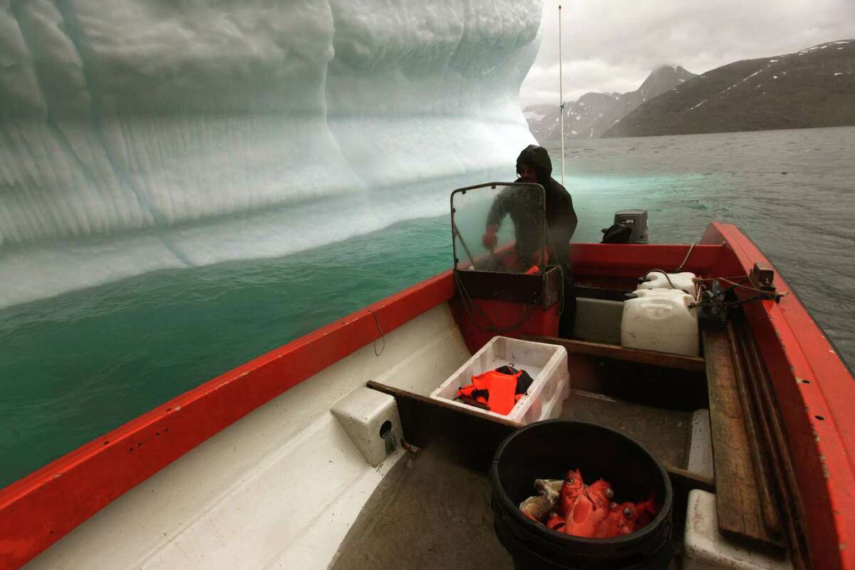 FILE - In this July 26, 2011 file photo, a Greenlandic Inuit hunter and fisherman steers his boat past a melting iceberg, along a fjord leading away from the edge of the Greenland ice sheet, near Nuuk, Greenland. Nearly 4 out of 5 Americans now think temperatures are rising and that global warming will be a serious problem for the United States if nothing is done about it, a new Associated Press-GfK poll finds. Belief and worry about climate change are inching up among Americans in general, but concern is growing faster among people who don't often trust scientists on the environment. In follow-up interviews, some of those doubters said they believe their own eyes as they've watched thermometers rise, New York City subway tunnels flood, polar ice melt and Midwestern farm fields dry up. (AP Photo/Brennan Linsley, File)