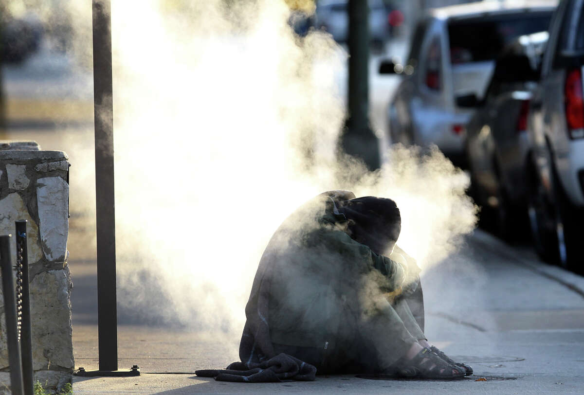 A man who appeared to be homeless tries to warm himself on a steaming grate on Market street near Alamo Tuesaday morning December 11, 2012. A police officer appeared moments later and told the man to leave. This morning's temperatures were in the lower 30s and tomorrow's low is predicted to be 34 degrees.