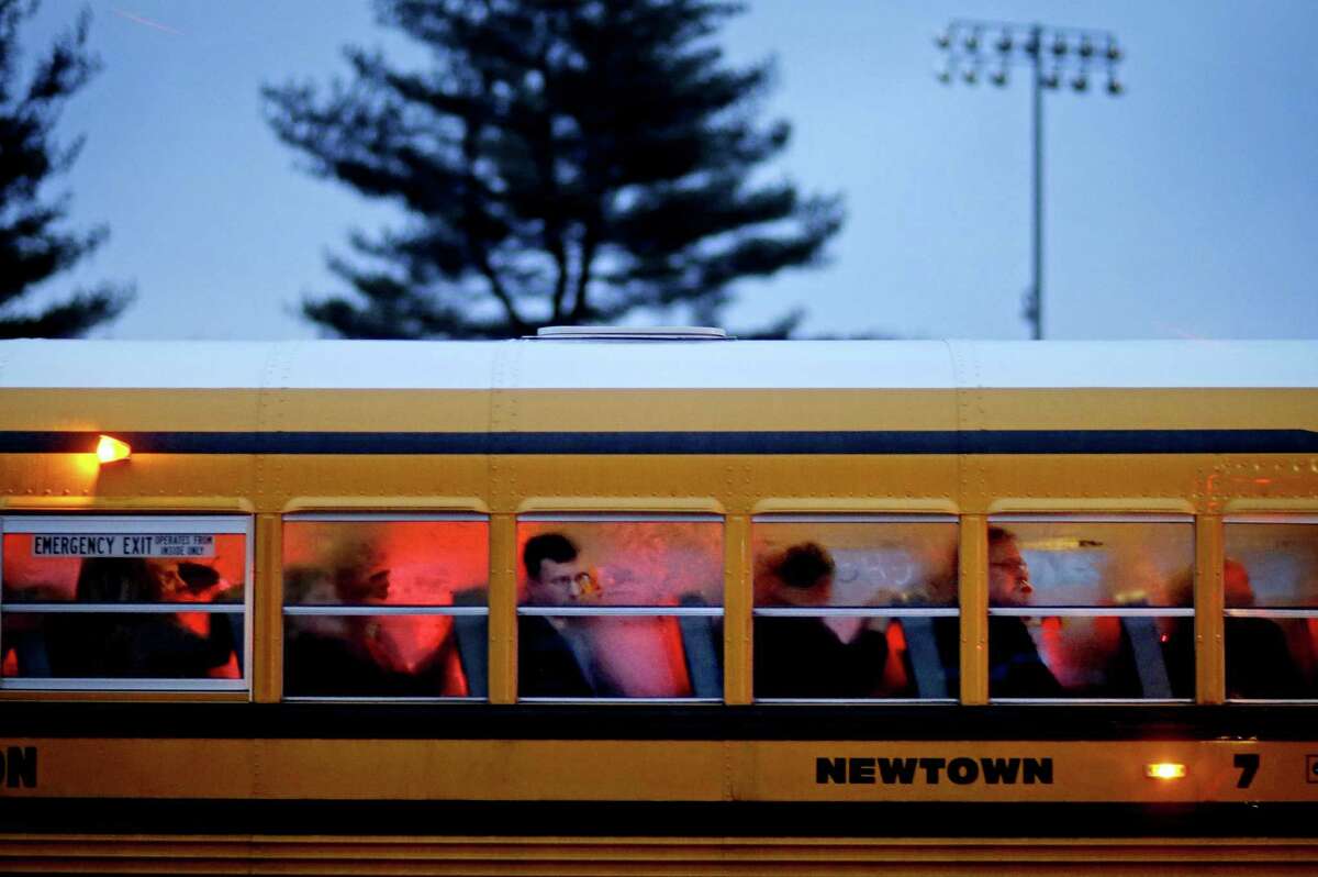 People arrive on a school bus at Newtown High School for a memorial vigil attended by President Barack Obama for the victims of the Sandy Hook Elementary School shooting, Sunday, Dec. 16, 2012, in Newtown, Conn. A gunman walked into Sandy Hook Elementary School in Newtown Friday and opened fire, killing 26 people, including 20 children. (AP Photo/David Goldman)