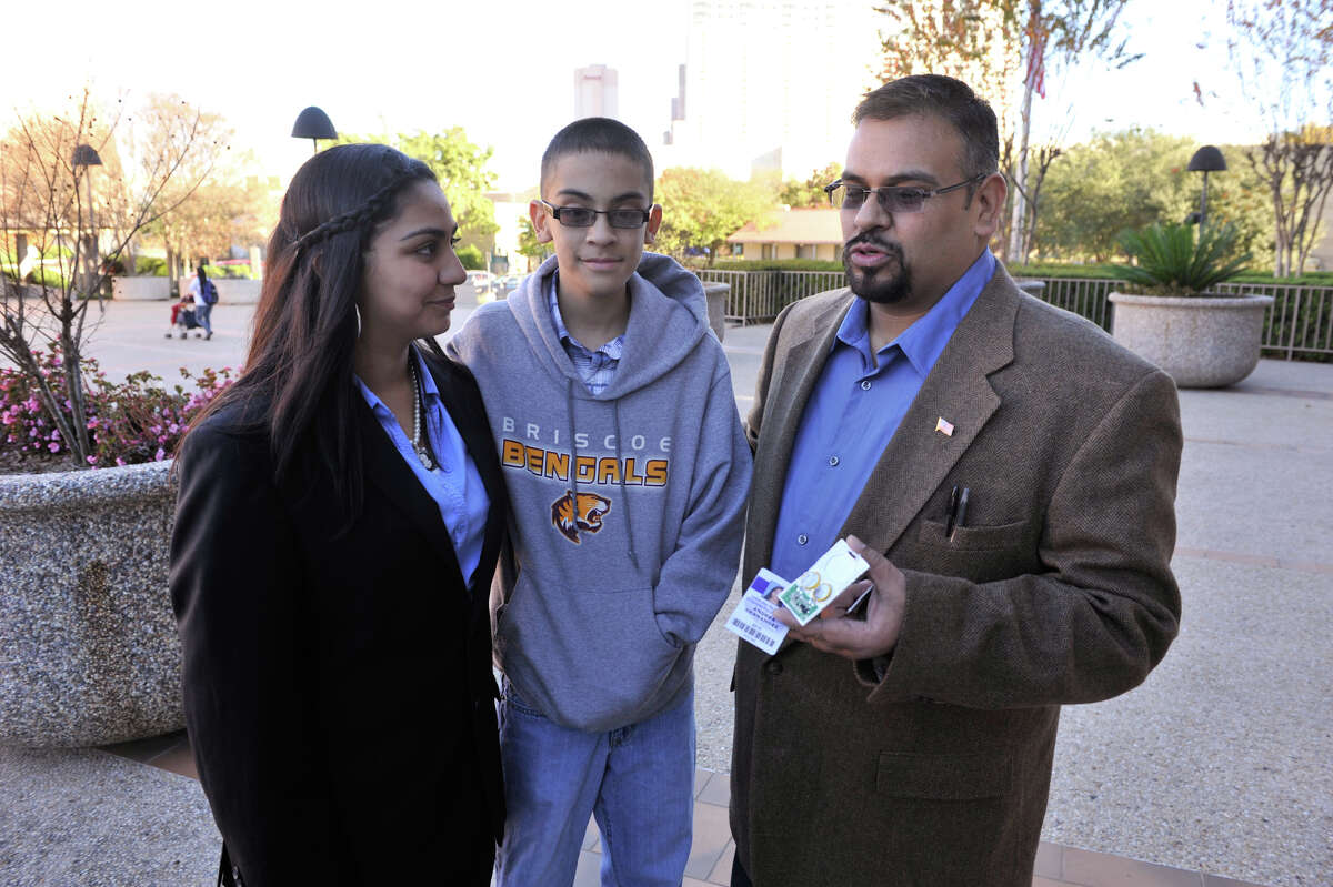 Steven Hernandez the father of NISD student Andrea Hernandez (left), along with son Vinson, 13, shows off the RFID equiped student ID in front of the San Antonio Federal Courthouse prior to a hearing.
