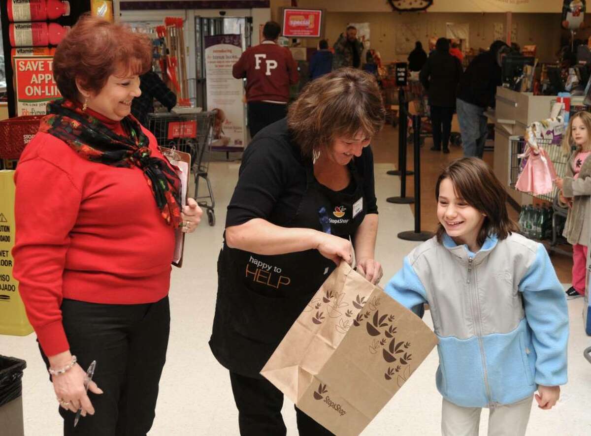 Mae Cimmino, left, of Sandy Hook, CT, looks on as, Karen Bertanza, center, of Shelton, CT, holds a bag of raffle tickets as, Angelina Ruggiero, right, 12, of Monroe, CT, draws a winning ticket during a fund raising event for the family of Becky Lohrenz, at Stop & Shop, in Newtown, CT, on Saturday, Dec. 19, 2009. Lohrenz, an employee of Stop & Shop, and the mother of two children, passed away earlier this year.