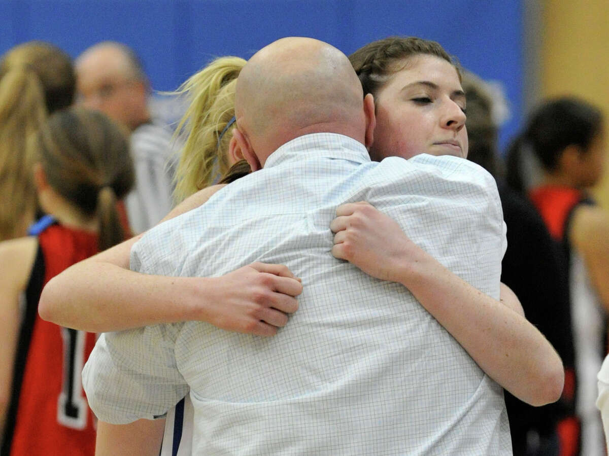 Newtown girls basketball head coach Jeremy O'Connell, back showing, hugs his team member Samantha Steimle after the Nighthawk's 64-44 win against Masuk at Newtown High School on Wednesday, Dec. 19, 2012. Wednesday's basketball game was the first sporting event in Newtown since the Sandy Hook Elementary School shooting.
