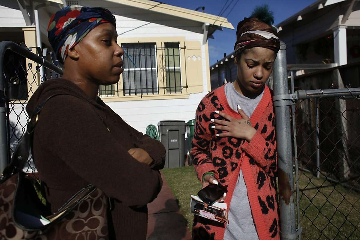 Janetta Roberts, left, and Aisha Roberts react as they remember their mother, Ramona Rochelle Foreman, Thursday Dec. 20, 2012, outside her home in Oakland, Calif. Foreman, was killed Wednesday night in the crossfire of two cars shooting at each other as she was walking down International Boulevard. She was the 124th homicide in Oakland this year.