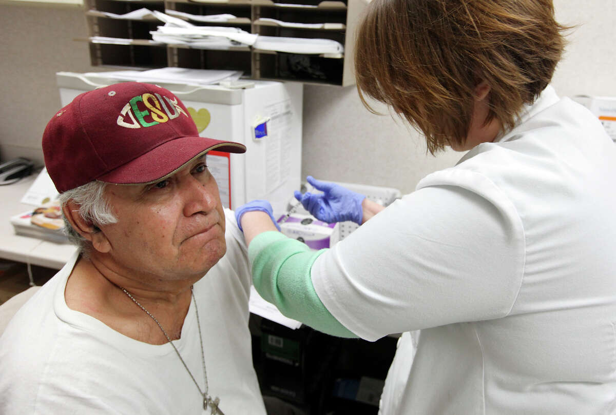 Manuel Reyes, 65, gets a flu shot from Walgreens staff pharmacist Amina Mhanna at the drugstore in the 7000 block of South Zarzamora Street.
