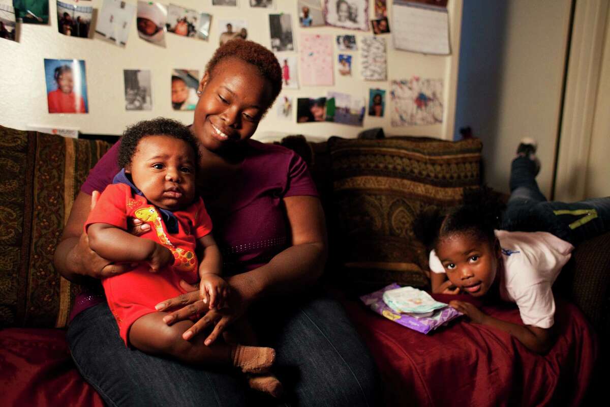 Single parent Twanna Davis sits for a family portrait with her 4-month-old son, Kaleb, and her 3-year-old daughter, Jazzlyn, at their Houston home.