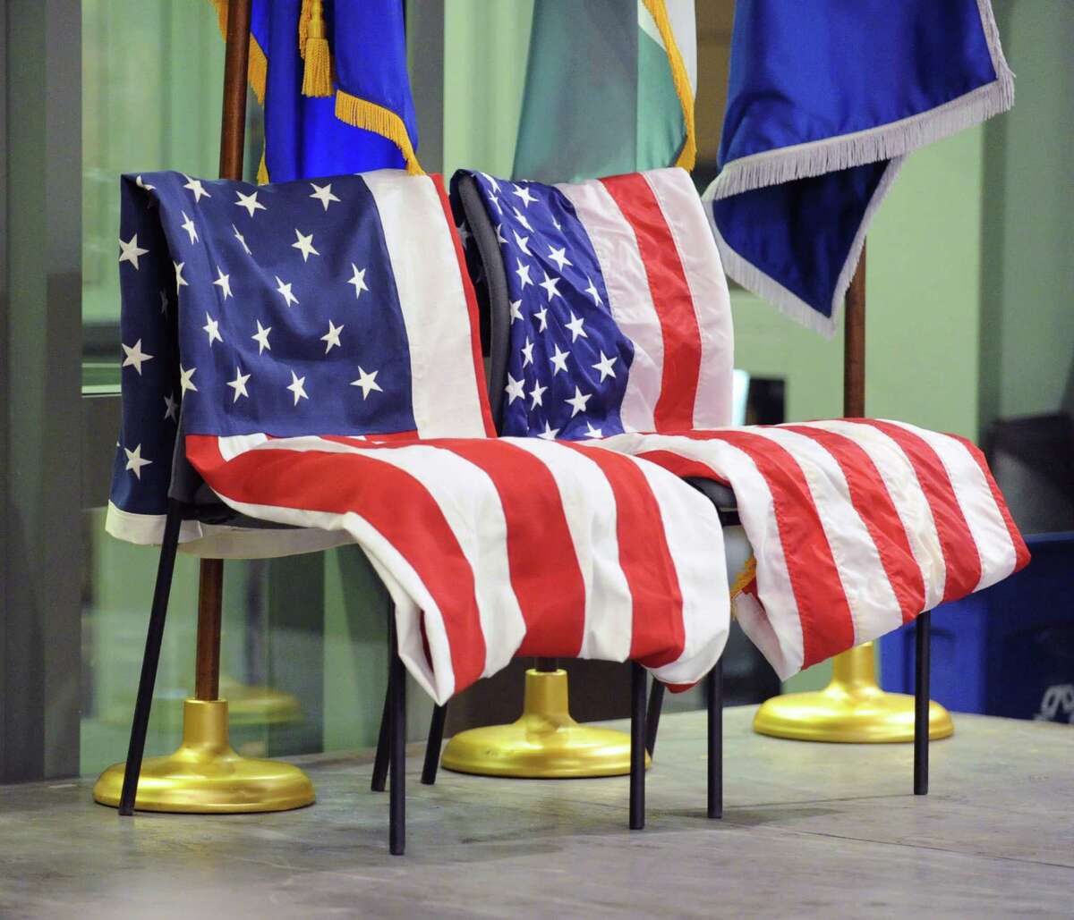 Two chairs are draped with American Flags honoring fallen servicemen, Lance Cpl. Joseph Schiano of the U.S. Marine Corps and First Sgt. Edwin Rivera of the Connecticut National Guard during the welcoming home ceremony for servicemen put on by the Greenwich Military Covenant of Care at Greenwich Police Headquarters, Thursday night, Dec. 20, 2012.