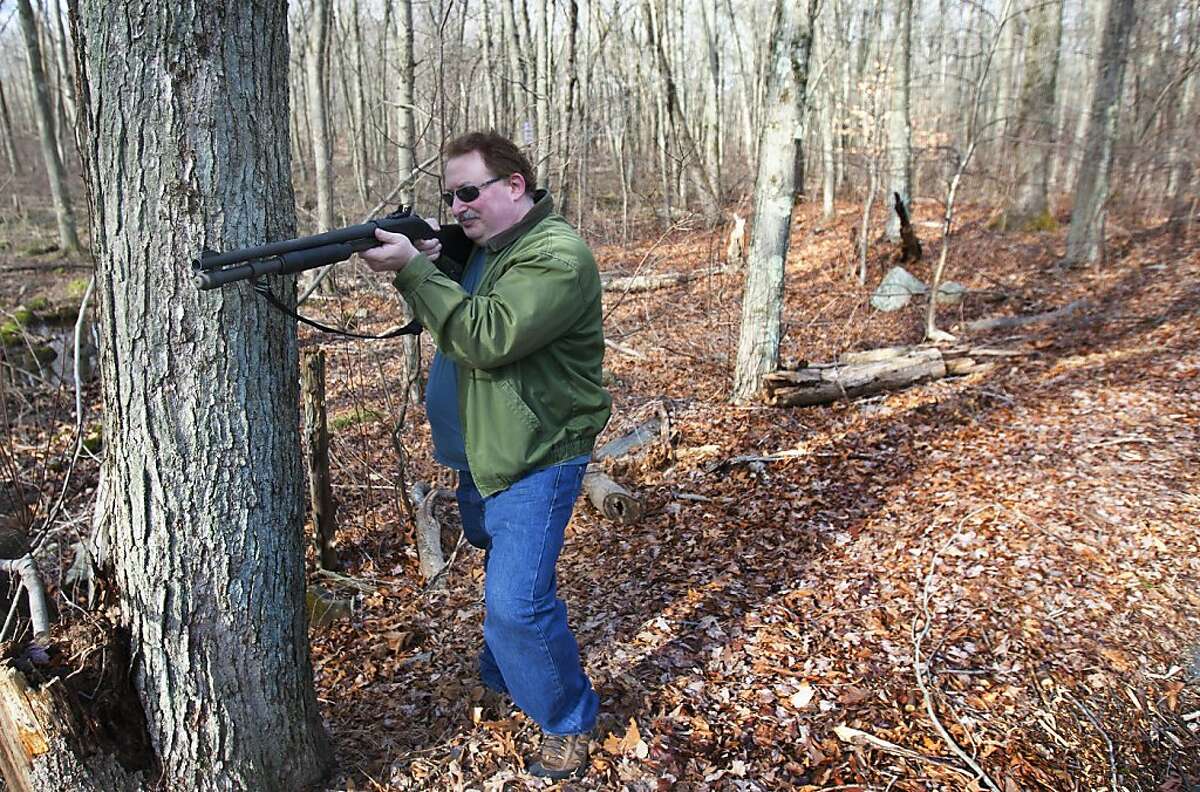 Adam Palmer holds up a shotgun in the woods Sunday, Dec. 23, 2012, in Ansonia. Palmer believes in being prepared with the right tools in case events take place such as natural disasters. "Every gun is a tool," Palmer said. "Like a shovel, every tool has its purpose." ( Cody Duty / Hearst Newspapers )