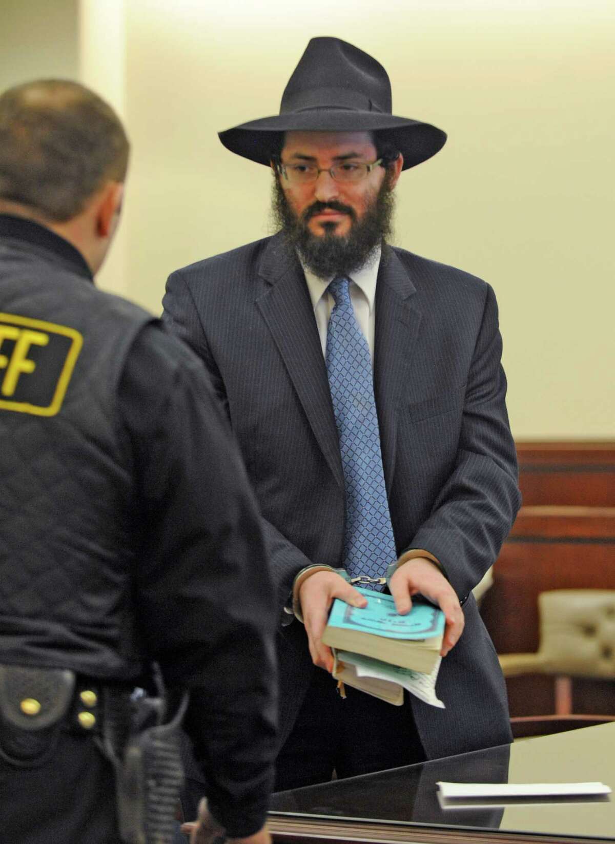 Rabbi Yaakov Weiss, formerly of Chabad of Colonie holds his prayer books and wears handcuffs after being sentenced to 60 days in Albany County Jail, his sentence for child endangerment in from Judge Stephen Herrick at the Albany County Judicial Center in Albany, New York March 8, 2010. (Skip Dickstein/Times Union)